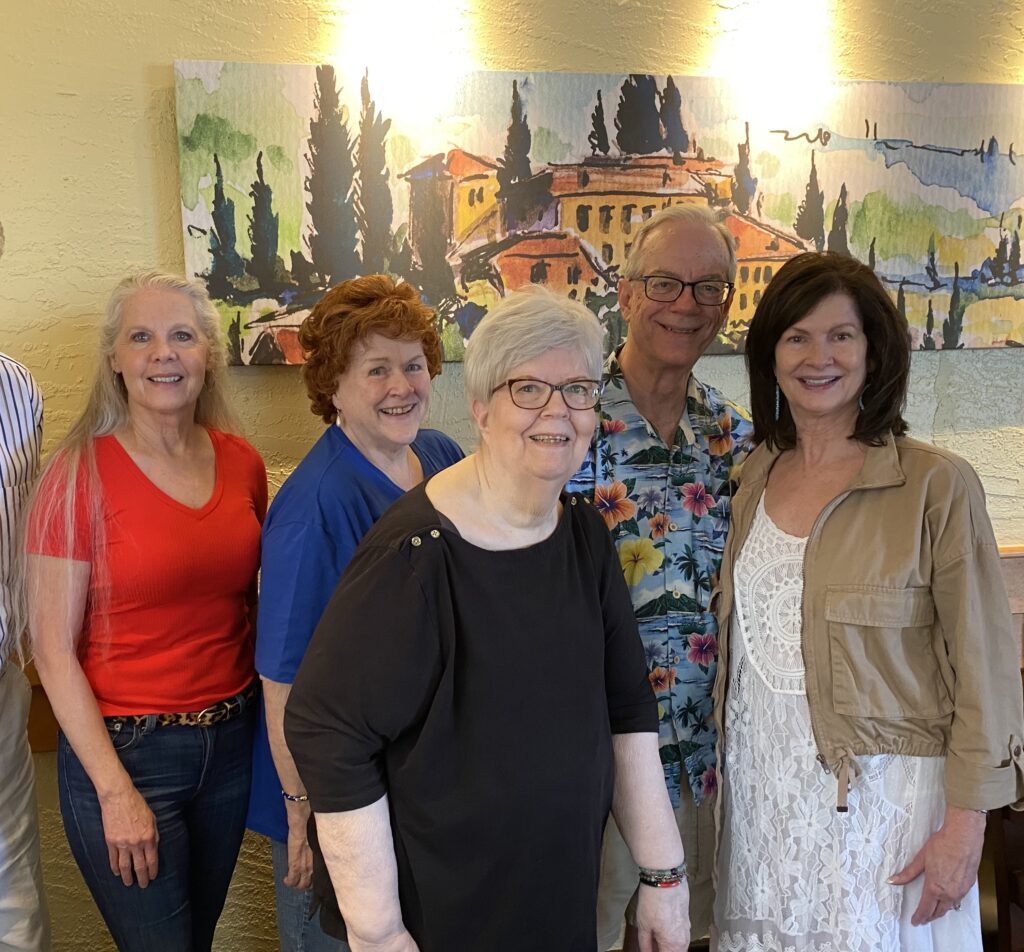 Five smiling adults posing indoors